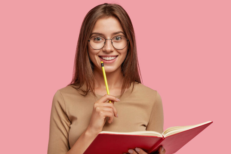 photo-happy-brunette-woman-with-positive-smile-carries-textbook-holds-pencil-writing